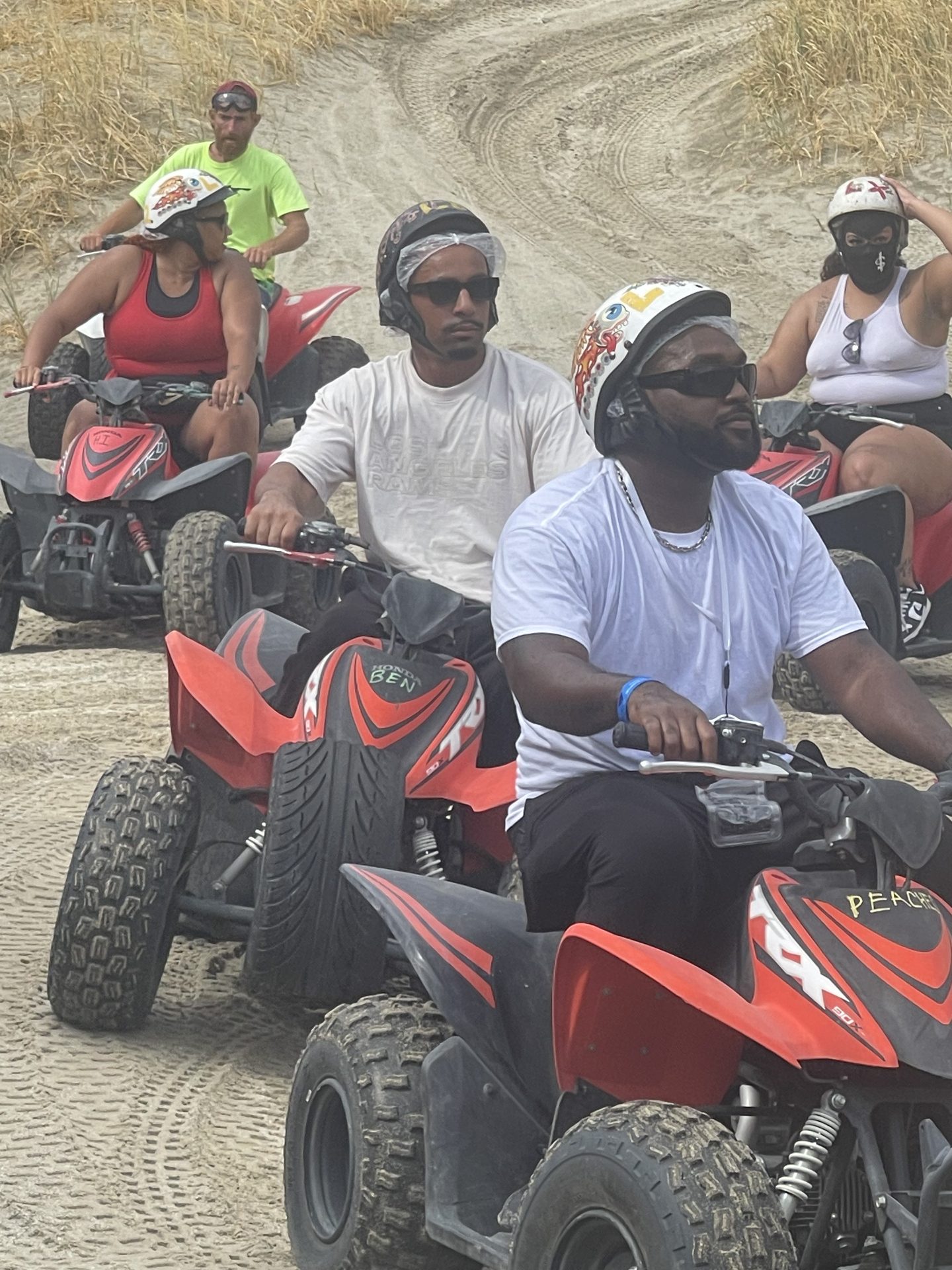 Family riding ATVs together across the dunes