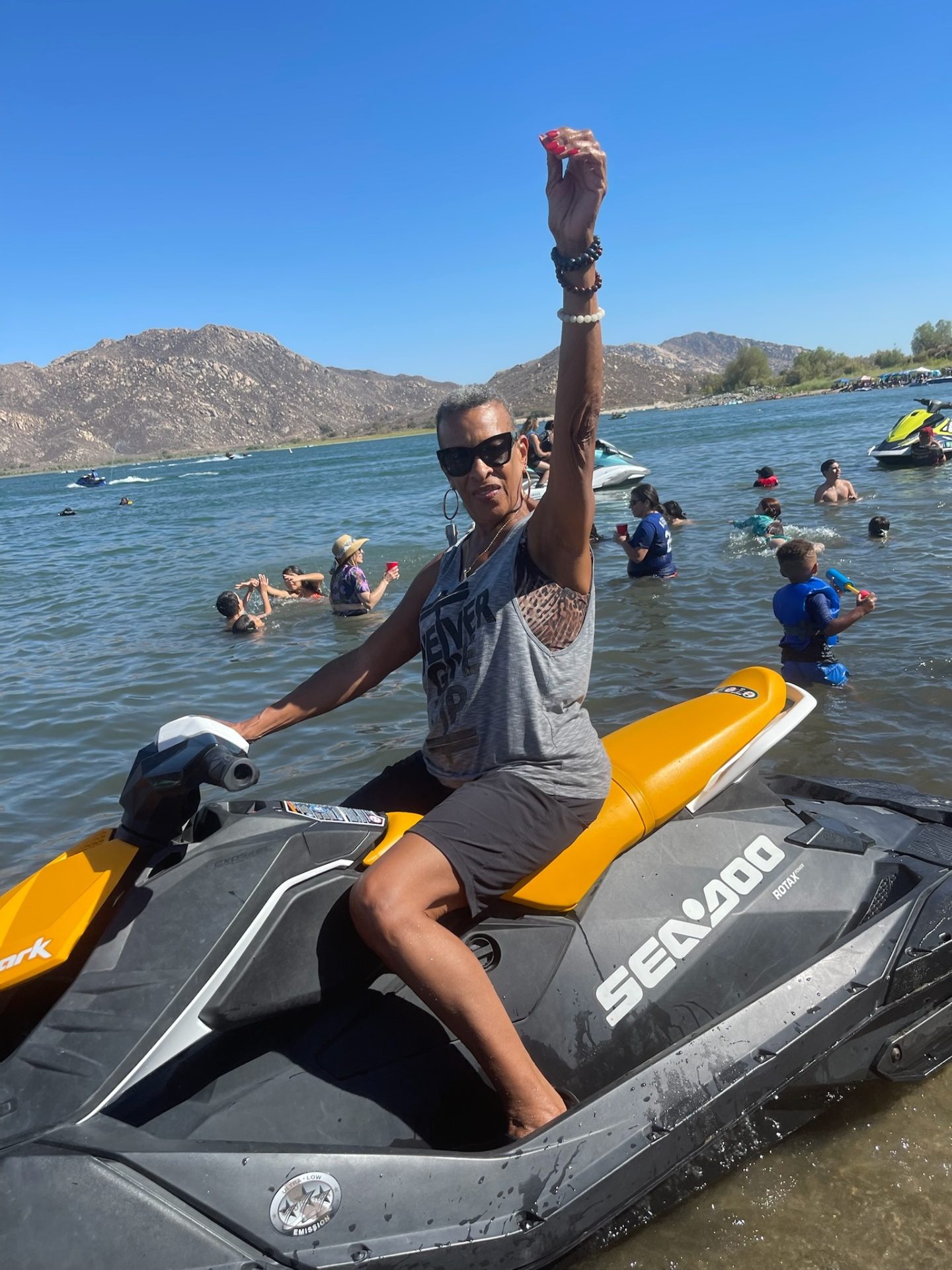 Grandma on a jet ski with her hand raised at the lake