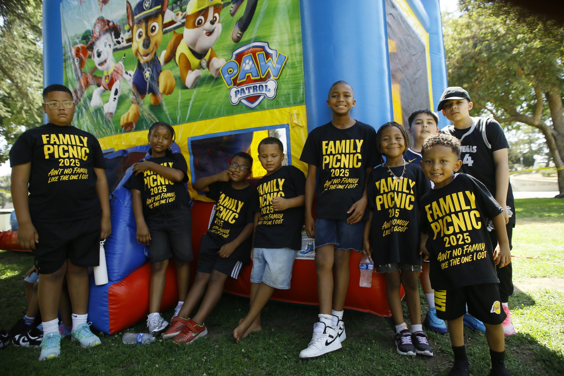 The kids in matching Family Picnic 2025 shirts by the bounce house